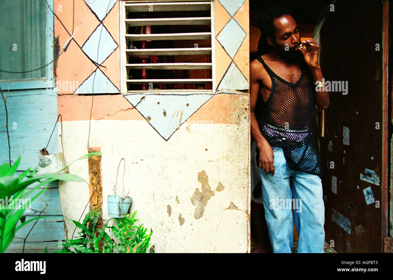 Noel toking on joint in doorway of his house in Judgement Yard Kingston Jamaica Stock Photo