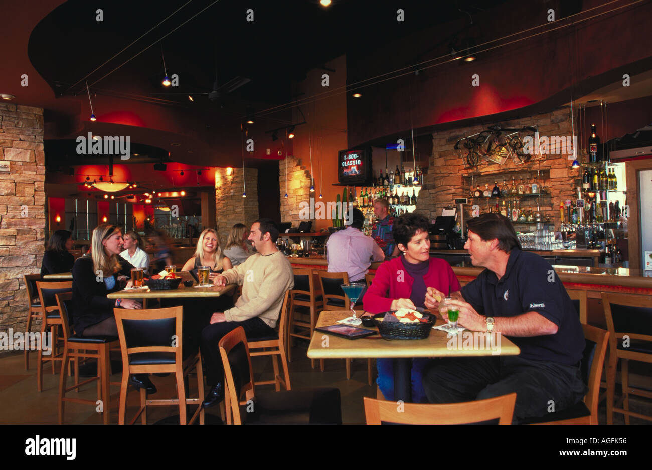 Patrons sitting in a bar at tables drinking and talking There is a man
