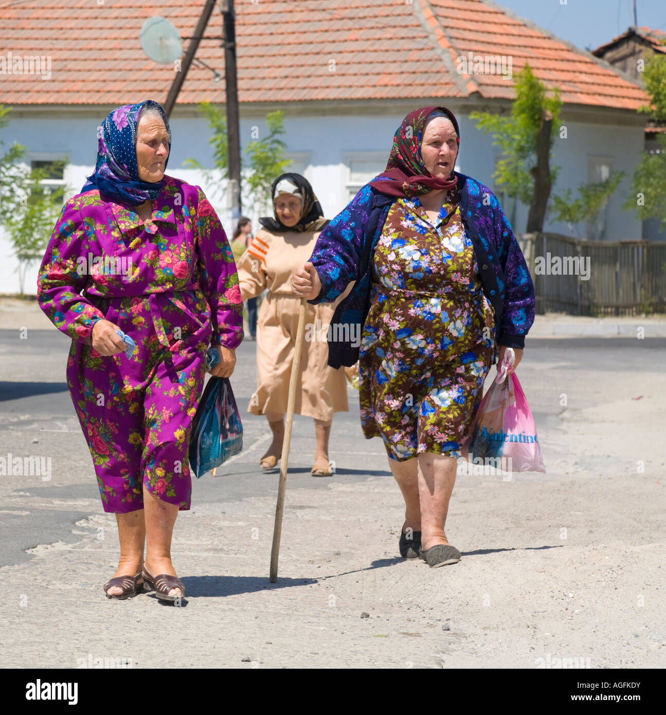 Three old women in traditional clothing crossing a street Stock Photo