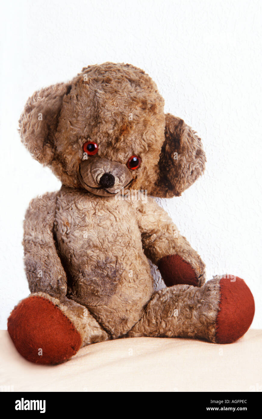 Well loved scruffy old teddy bear seated Stock Photo