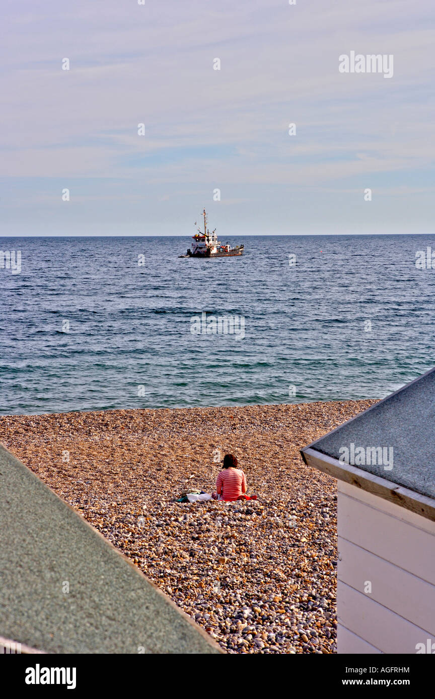 A woman sitting alone on the beach in Branscombe Devon England Stock Photo