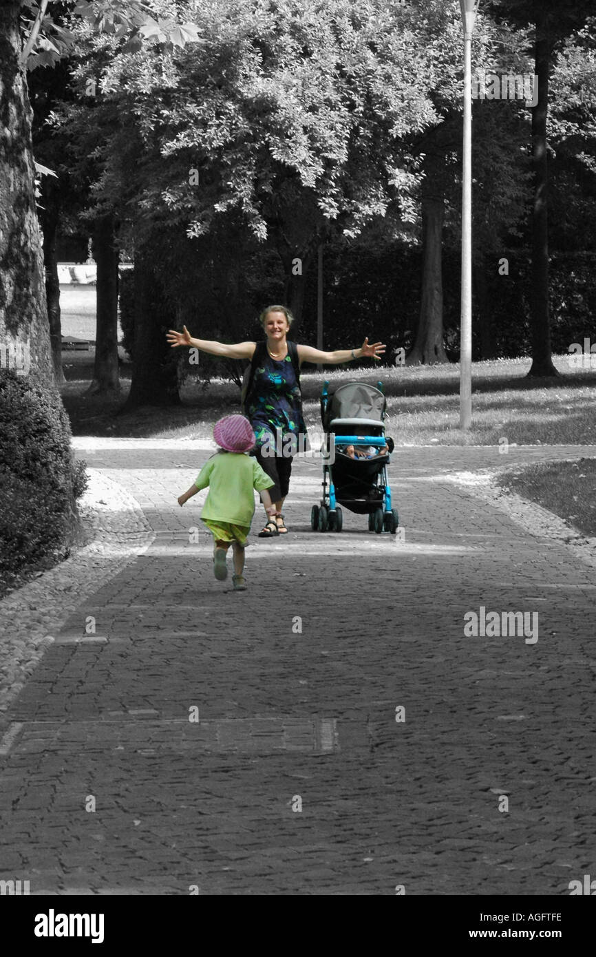 infant running in the arms of her mother waiting with a pram Stock Photo