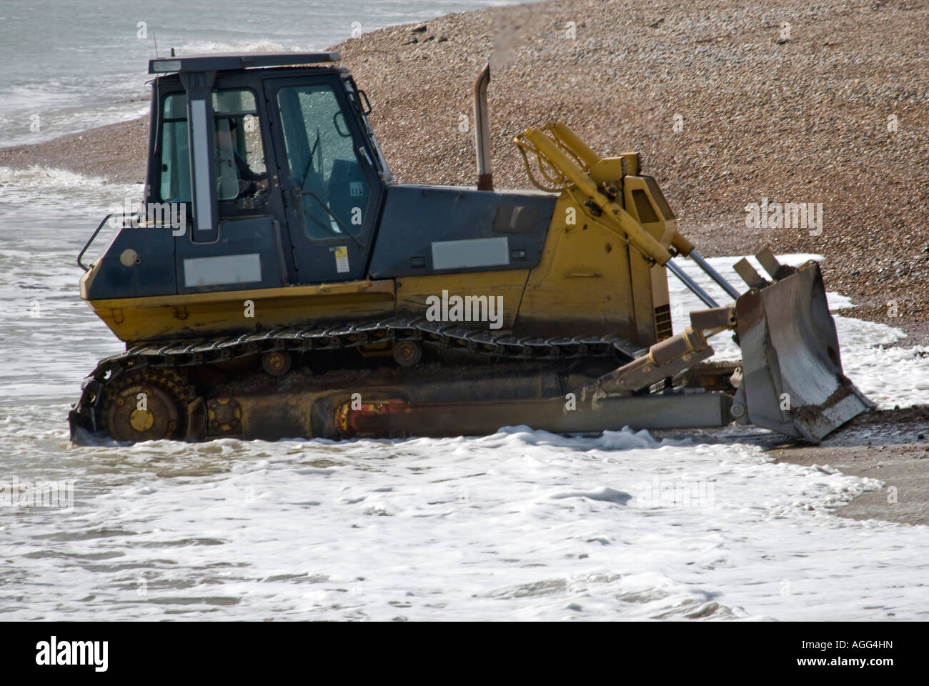 BULLDOZER PUSHING SHINGLE WORKING ON THE BEACH Stock Photo