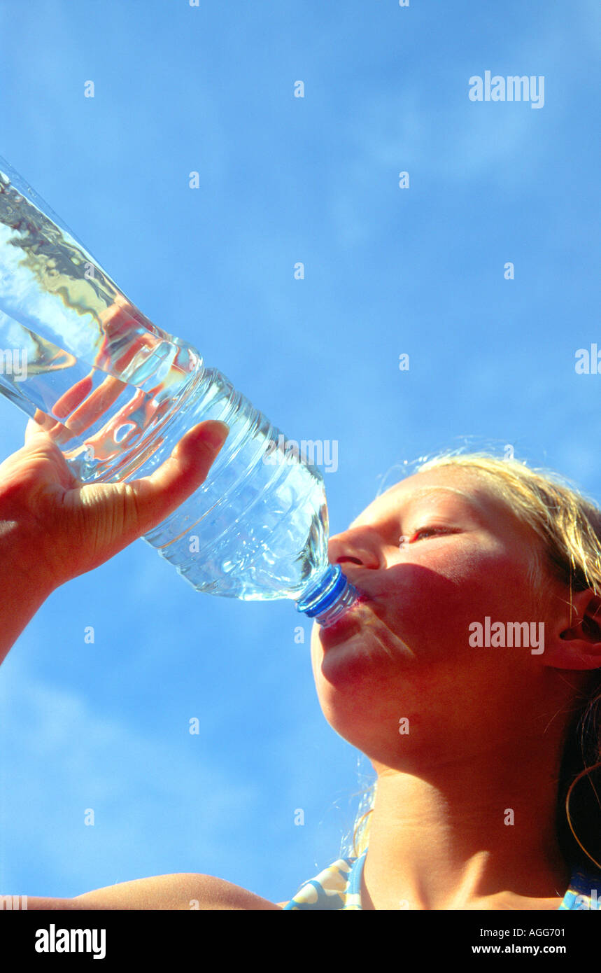 Blue sky young girl drinking bottled water Stock Photo