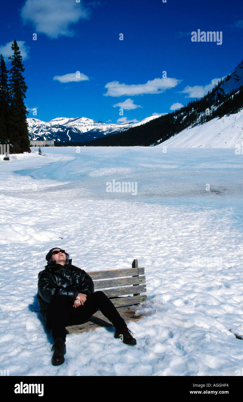 female tourist sunbathing on a bench at the frozen lake louise banff national park alberta canada Stock Photo