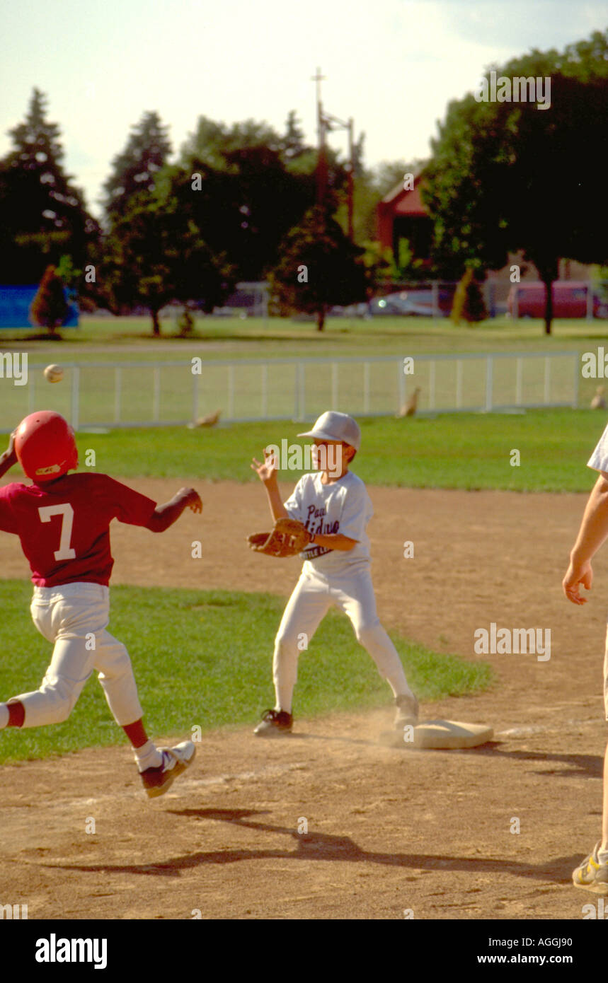 Boys age 12 at Dunning Field baseball game running for first base. St Paul Minnesota USA Stock Photo