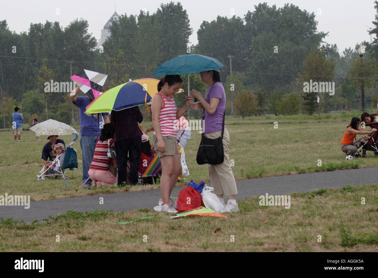 Mother and Daughter share an umbrella at Kite Festival in Liberty State Park across from Manhattan Stock Photo