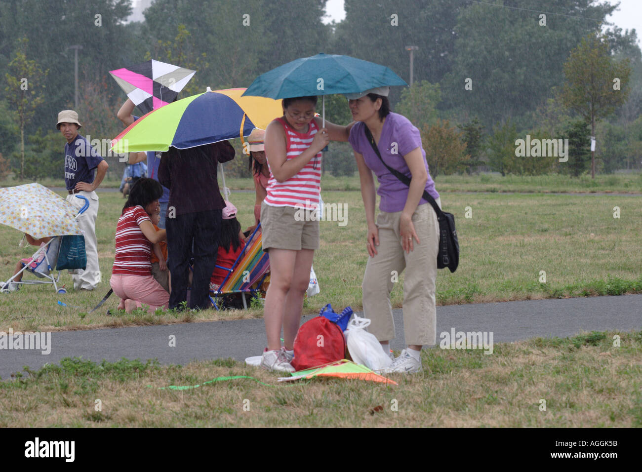 Mother and Daughter share an umbrella at Kite Festival in Liberty State Park across from Manhattan Stock Photo