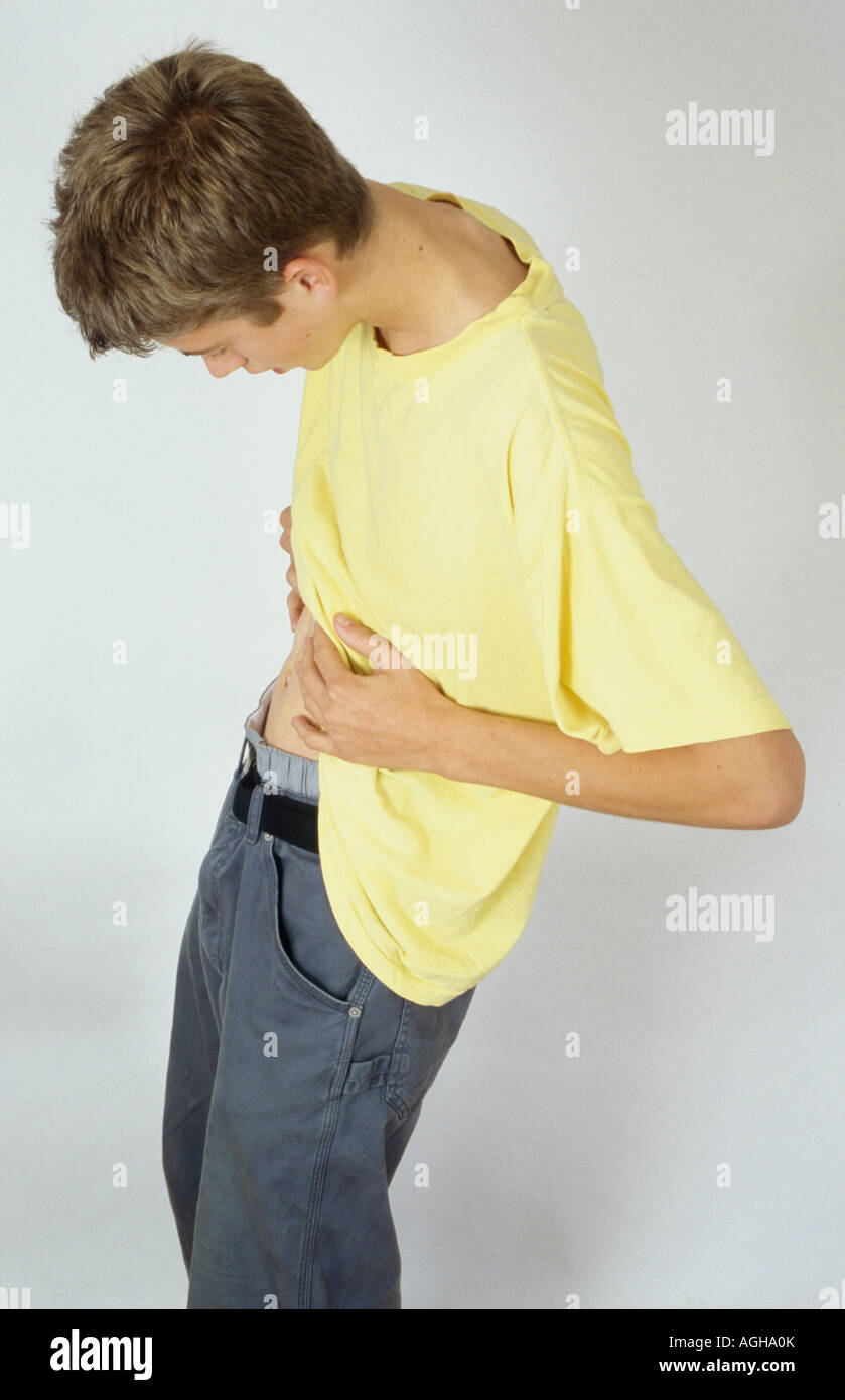 thin teenage boy lifting his t shirt to look at his stomach Stock Photo