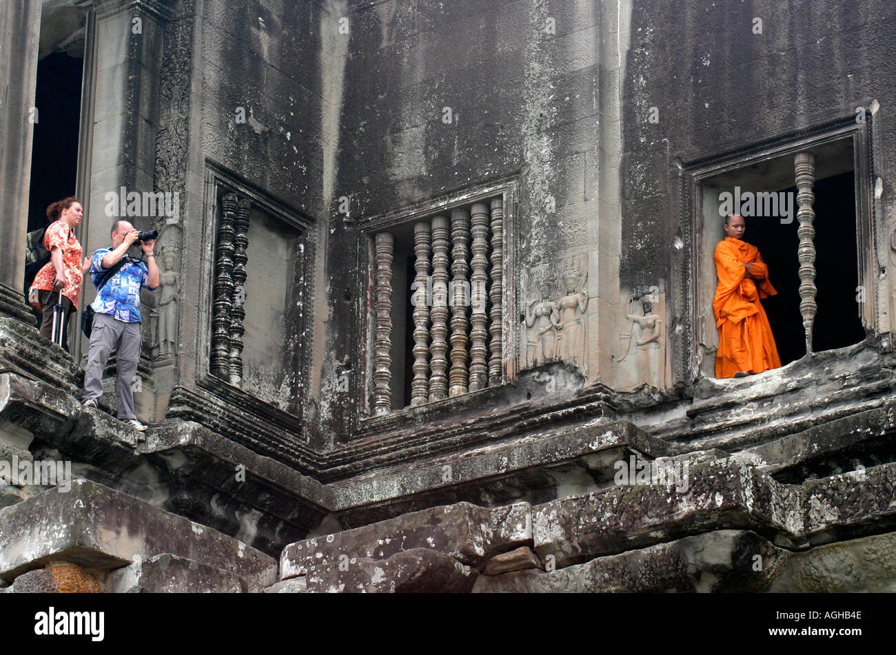 Buddhist monk and tourist couple standing in windows. Angkor Wat, Cambodia Stock Photo