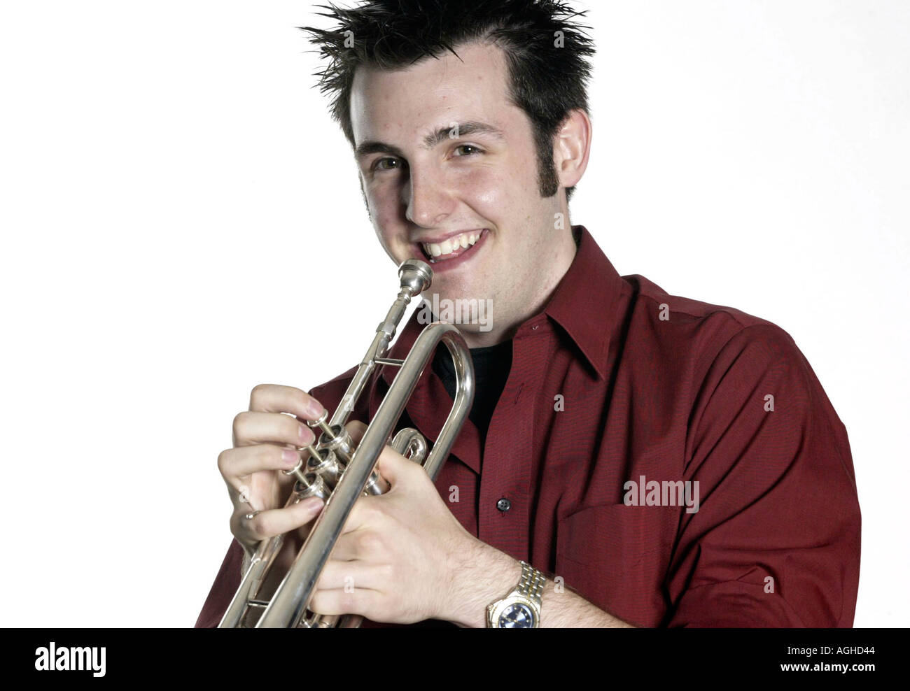A college age man holds a trumpet cornet horn Stock Photo