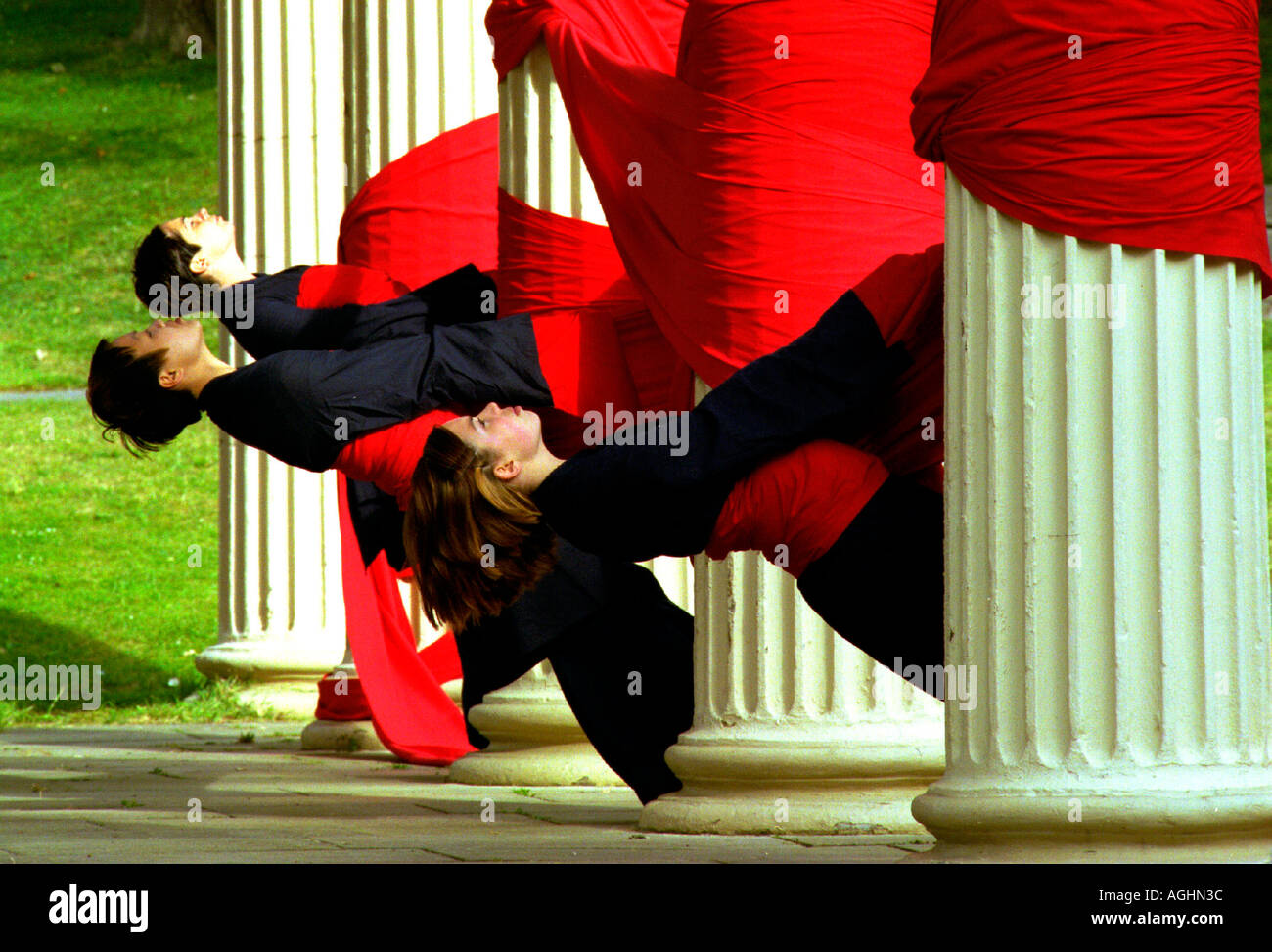 Lithe young dancers with red cloth and giant pillars at a university graduate show. Stock Photo