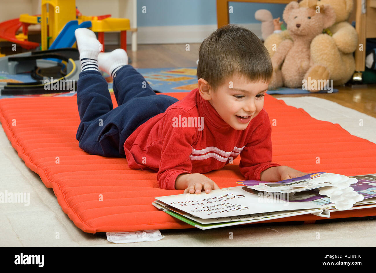 three year old boy lies on floor and looks at a pop up picture book Stock Photo