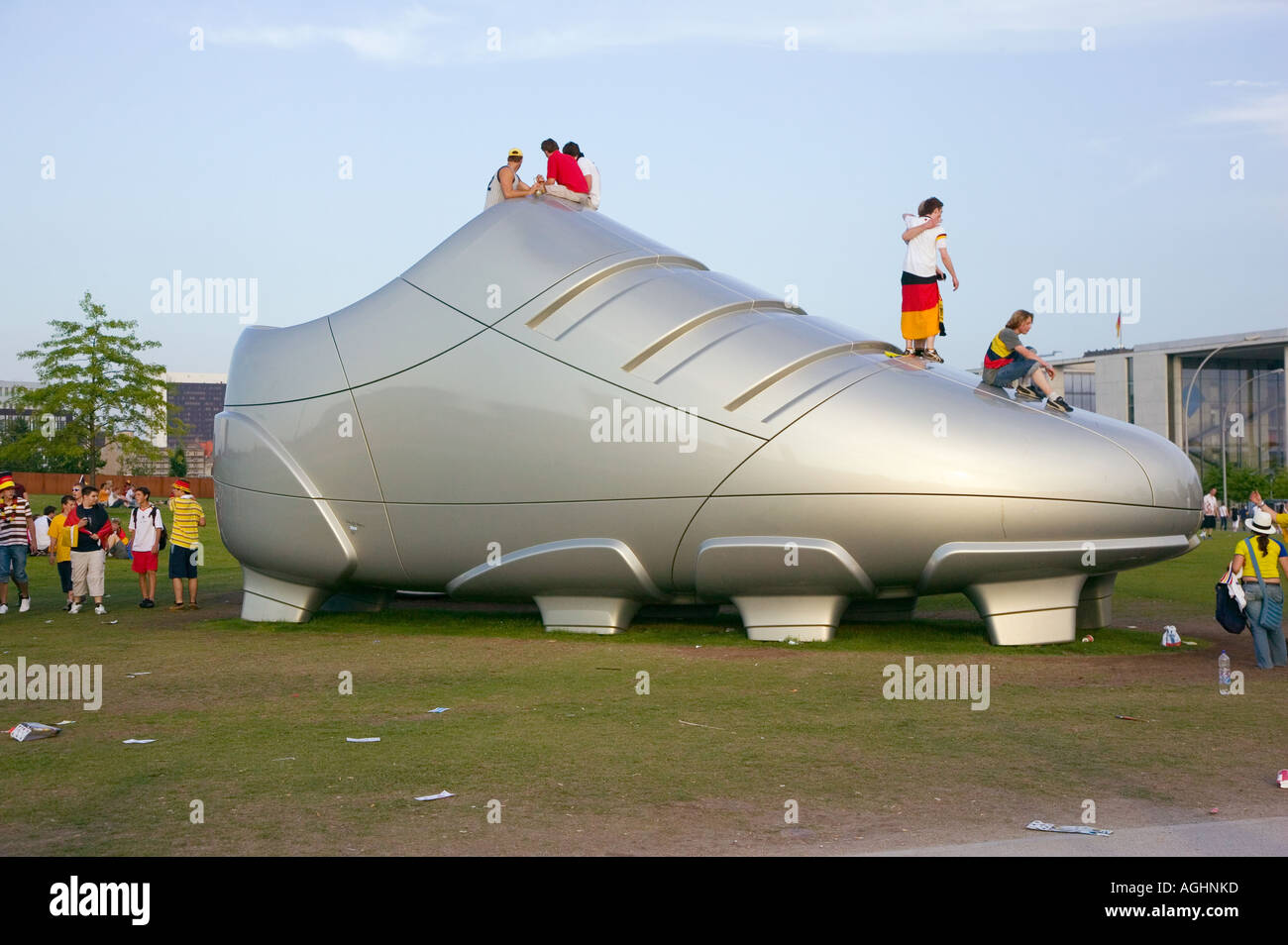 Fans climb on a giant soccer shoe near the Fan Fest during the World