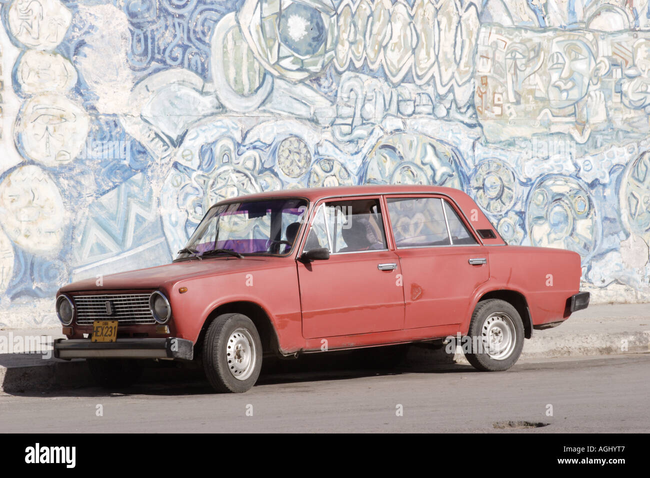 Red Lada parked by a mural in Havana, Cuba Stock Photo