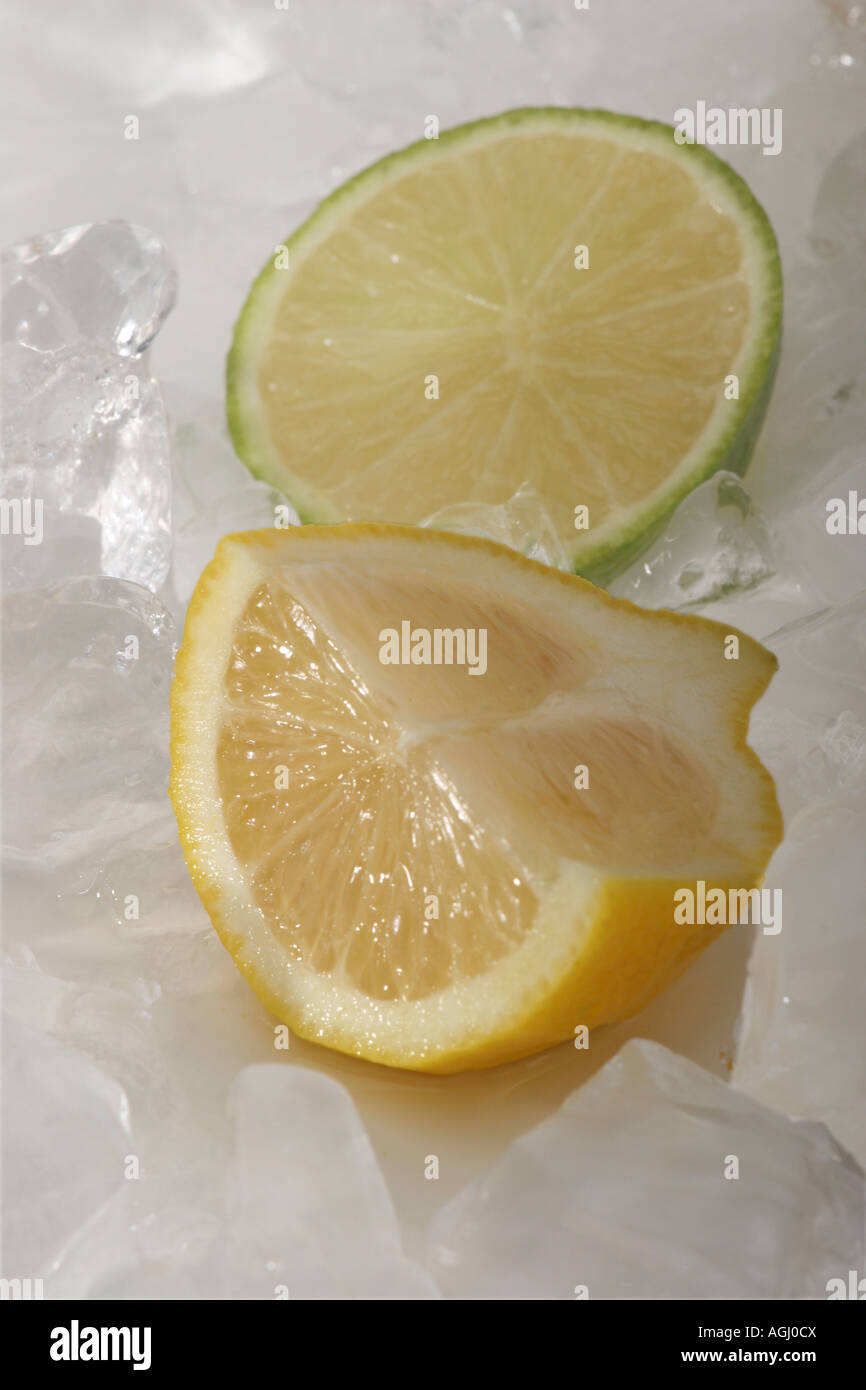 Close up of fresh organic piece yellow lemon hi-res with ice cubes and a slice of green lime from above overhead nobody vertical from above hi-res Stock Photo