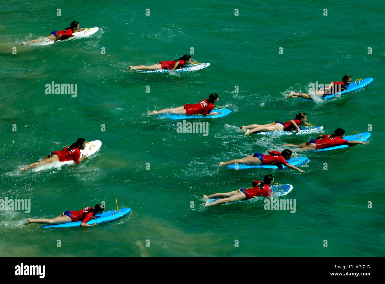 An aerial view of young girls training with surfboards as surf