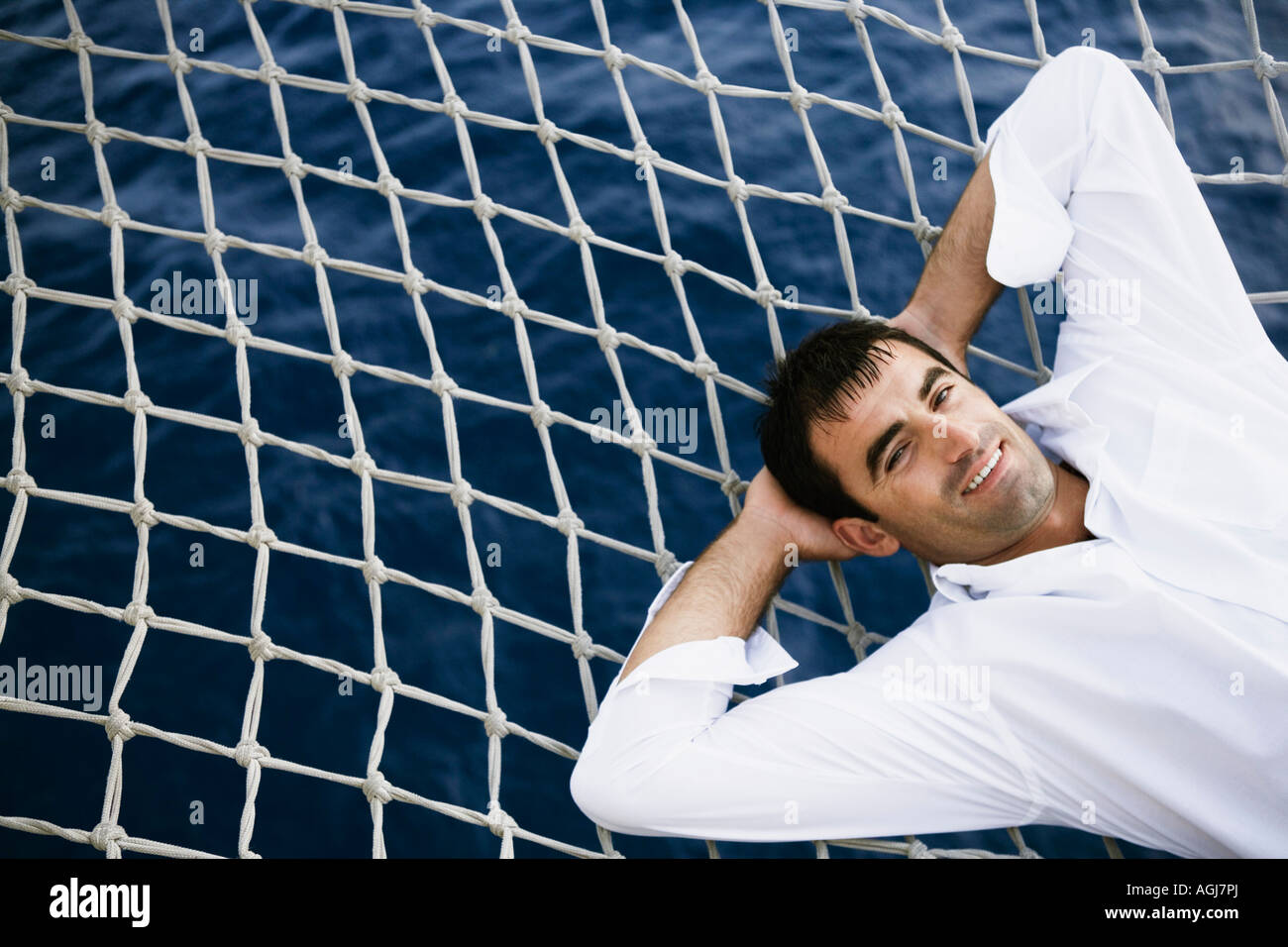 Portrait of a mid adult man lying on a net and smiling Stock Photo - Alamy