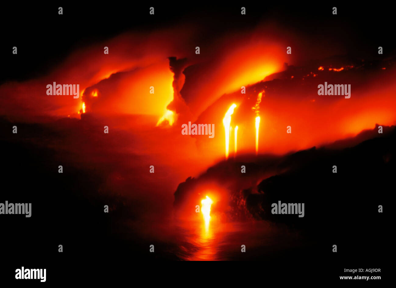 Lava flowing into sea at night Stock Photo