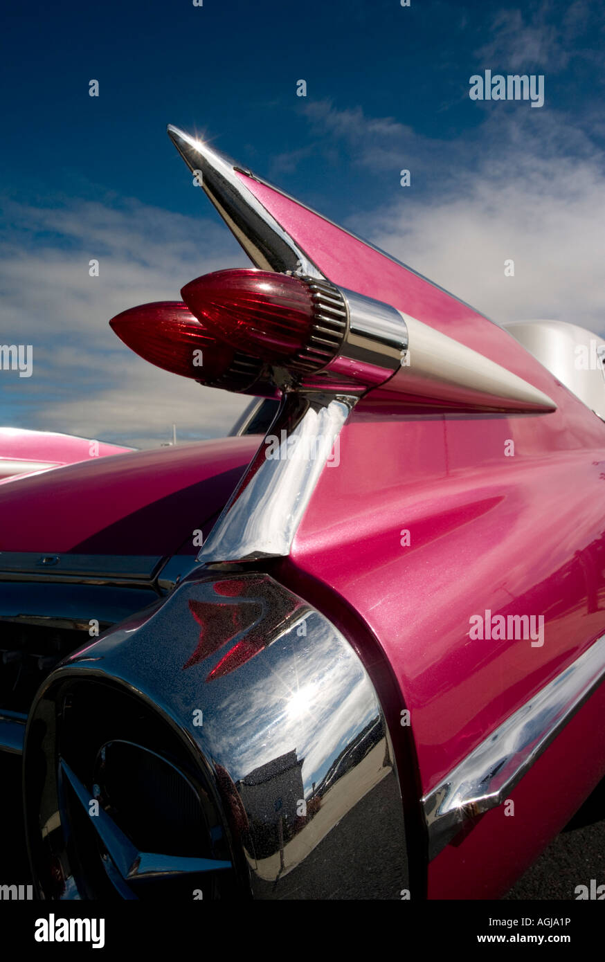 Iconic Chrome fins and tail lights on a pink 1959 Cadillac Coupe de Ville classic car with blue sky Stock Photo