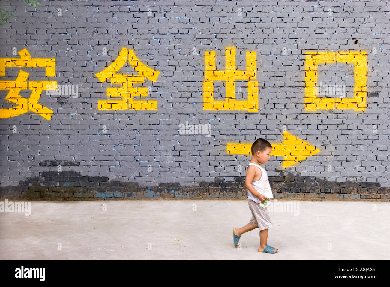 Asia China Peking young boyx on the road in front of wall with Chinese characters Stock Photo