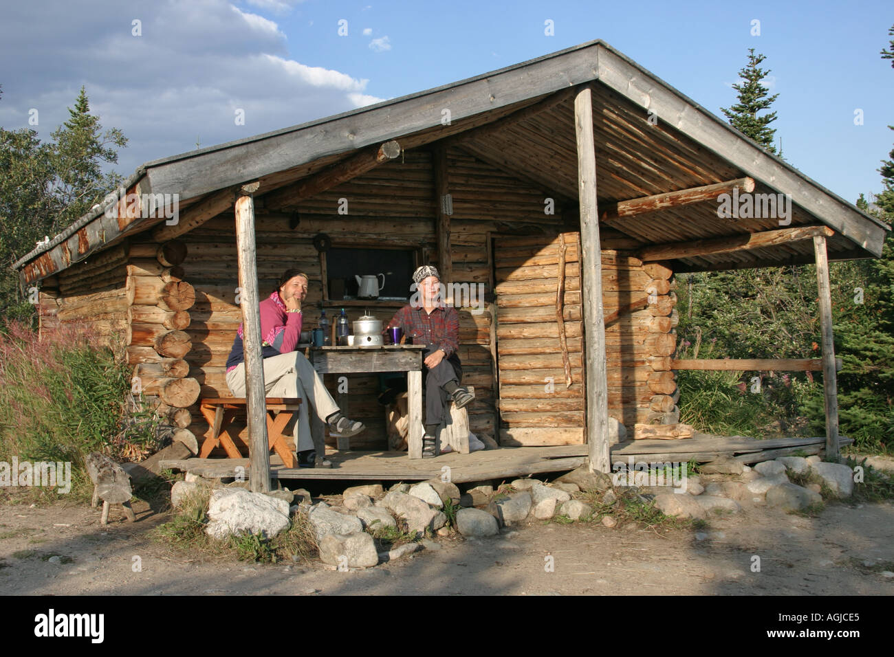 MR couple sits under the canopy of a cosy log hut at the Lake Lindemann Chilkoot Trail British Columbia Canada Stock Photo