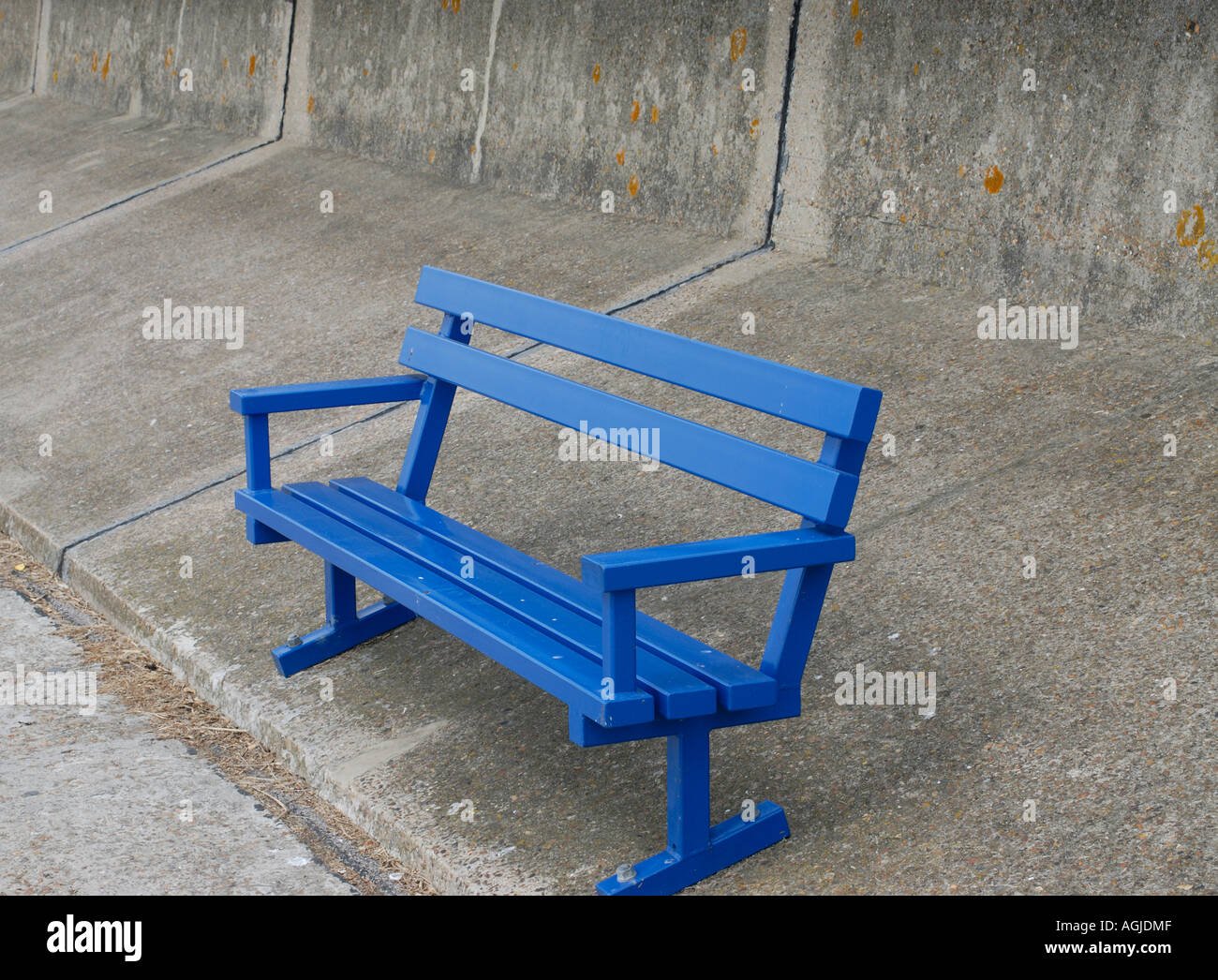 Blue bench on a grey concrete sea wall Queensborough Isle of Sheppey UK