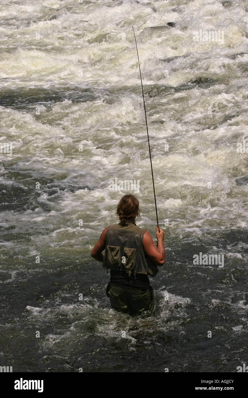 River Little Manistee MI USA young fisherman fly fishing with a rod in the closeup of Caucasian man stands in water wearing a fishing vest hi-res Stock Photo