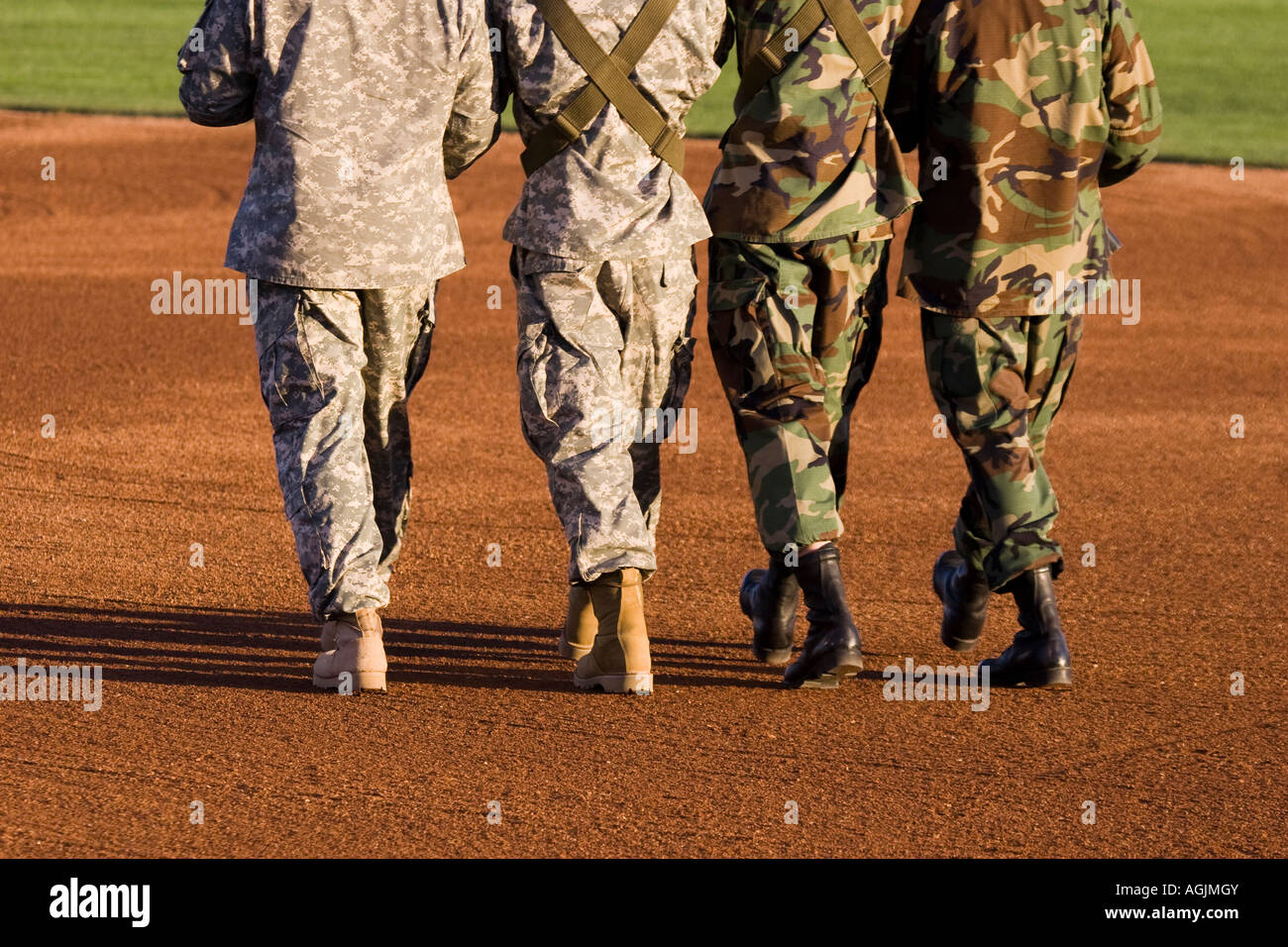 Four soldiers in military camouflage uniforms marching in unison. Stock Photo