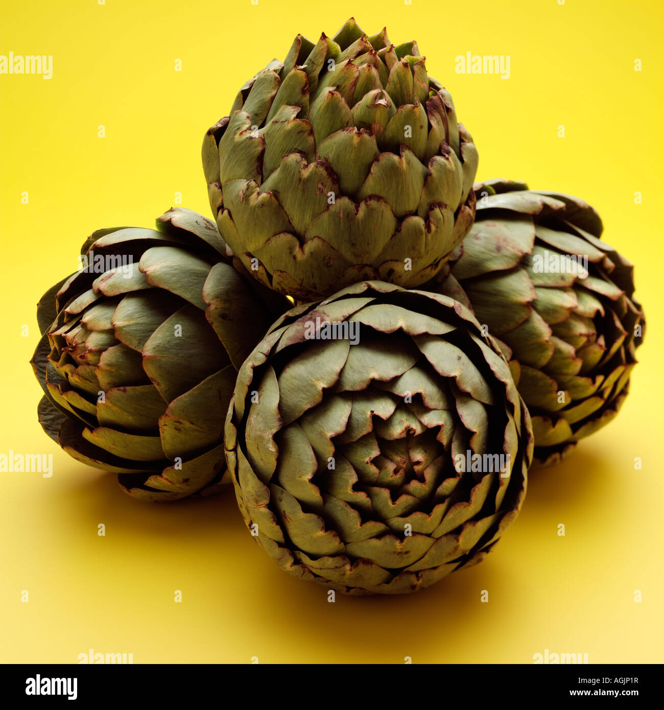 A pile of whole artichokes on a yellow background Stock Photo Alamy