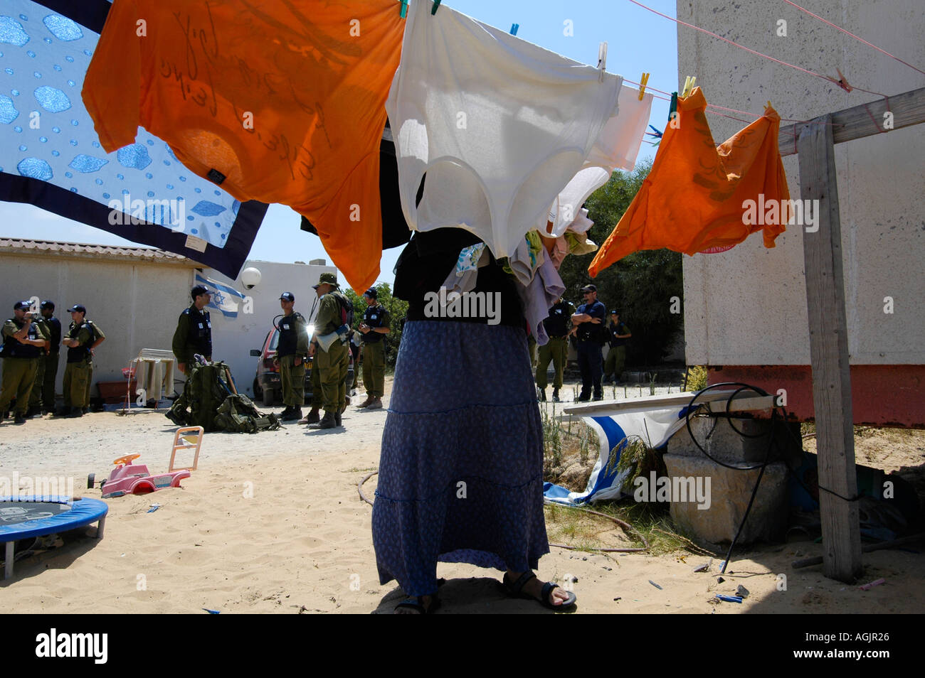 A settler hangs laundry as Israeli soldiers wait to remove settlers from Tel Katifa Jewish settlement as part of the Israeli disengagement from Gaza Stock Photo