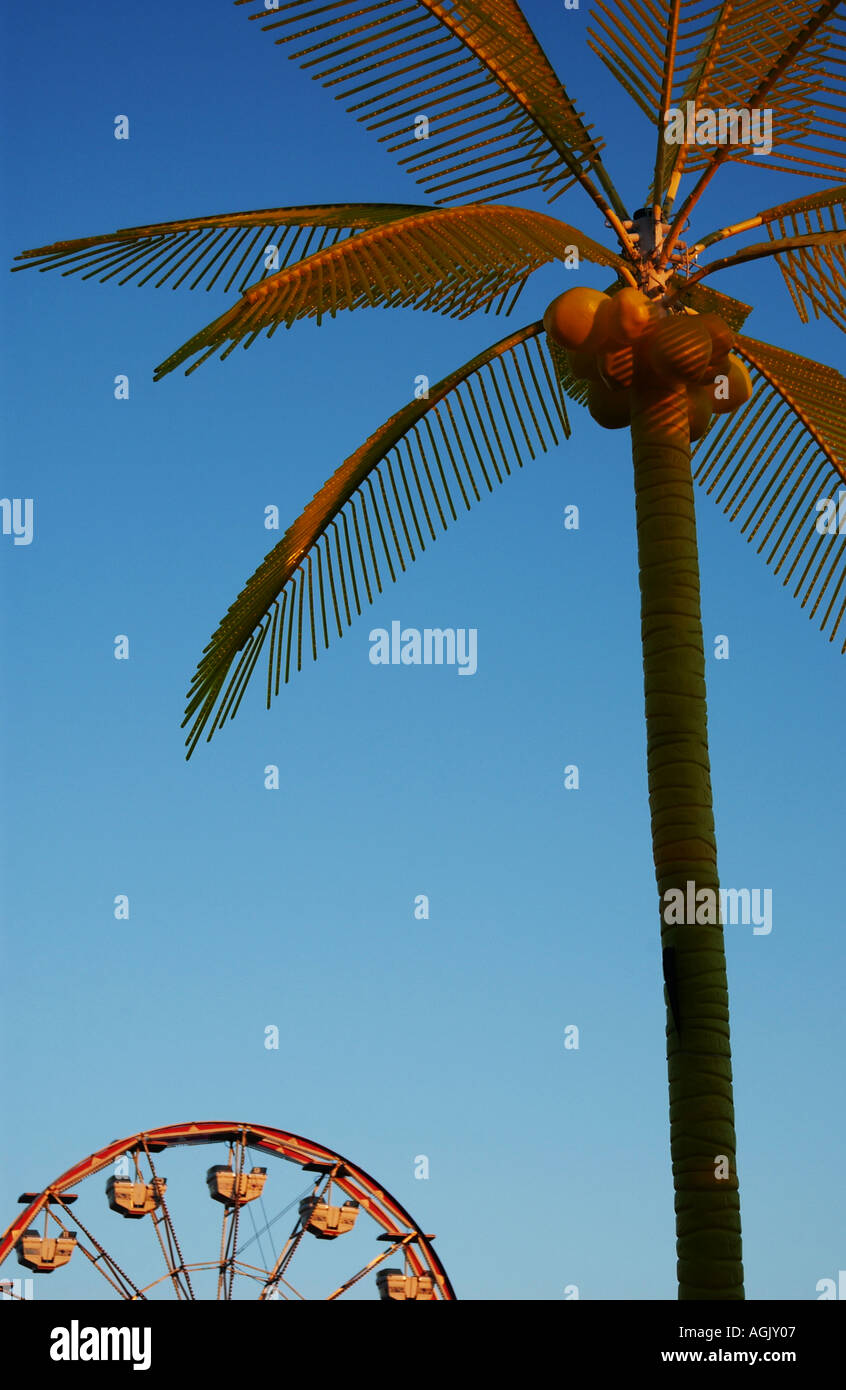 Fake plastic yellow palm tree and ferris wheel in front of blue sky