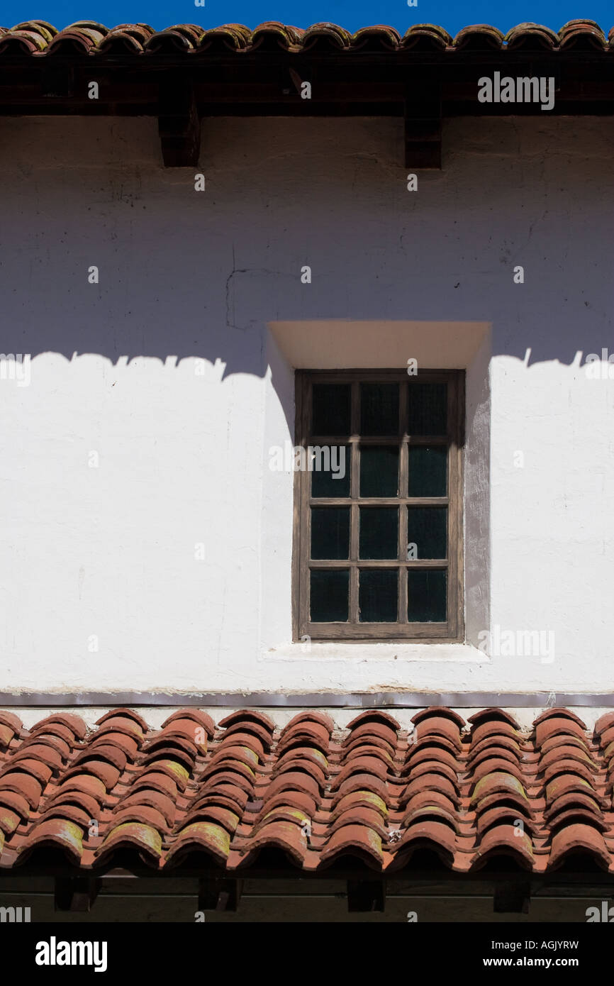 One wood window and Spanish tile roofs casting shadows on white walls