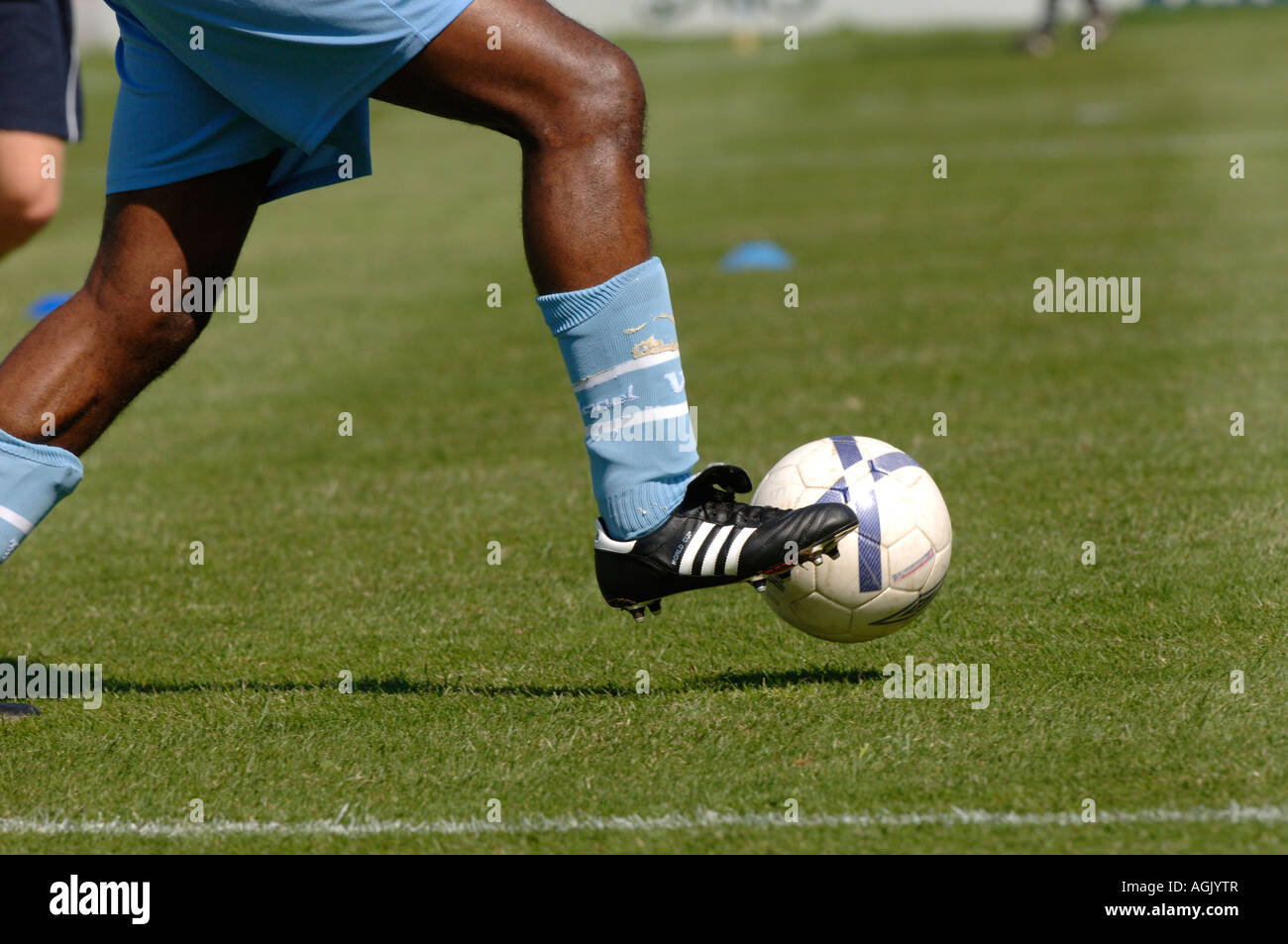 A footballer kicking a ball around, warming up before a match. Stock Photo