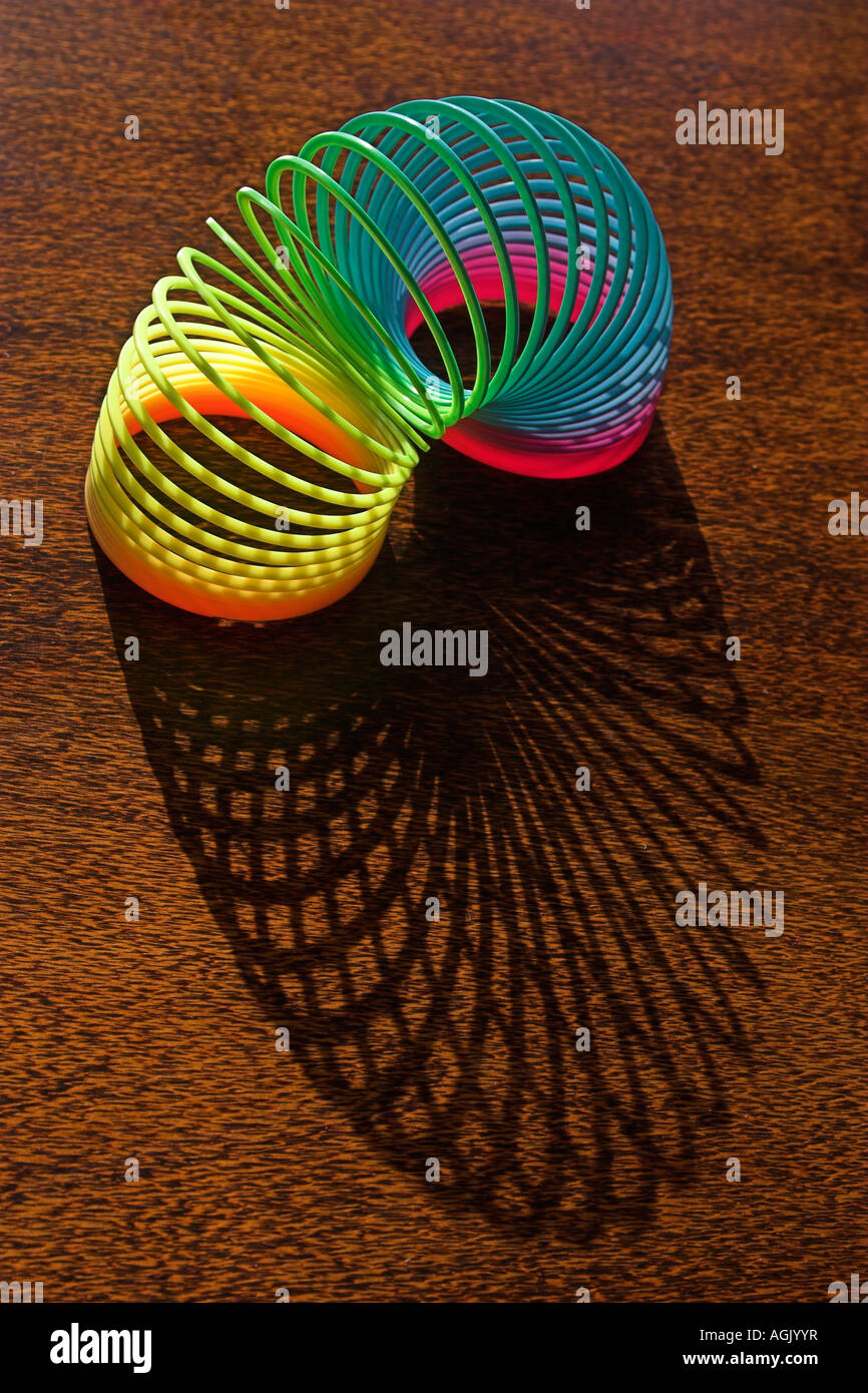 A childs toy slinky casts a shadow on a wooden table Stock Photo