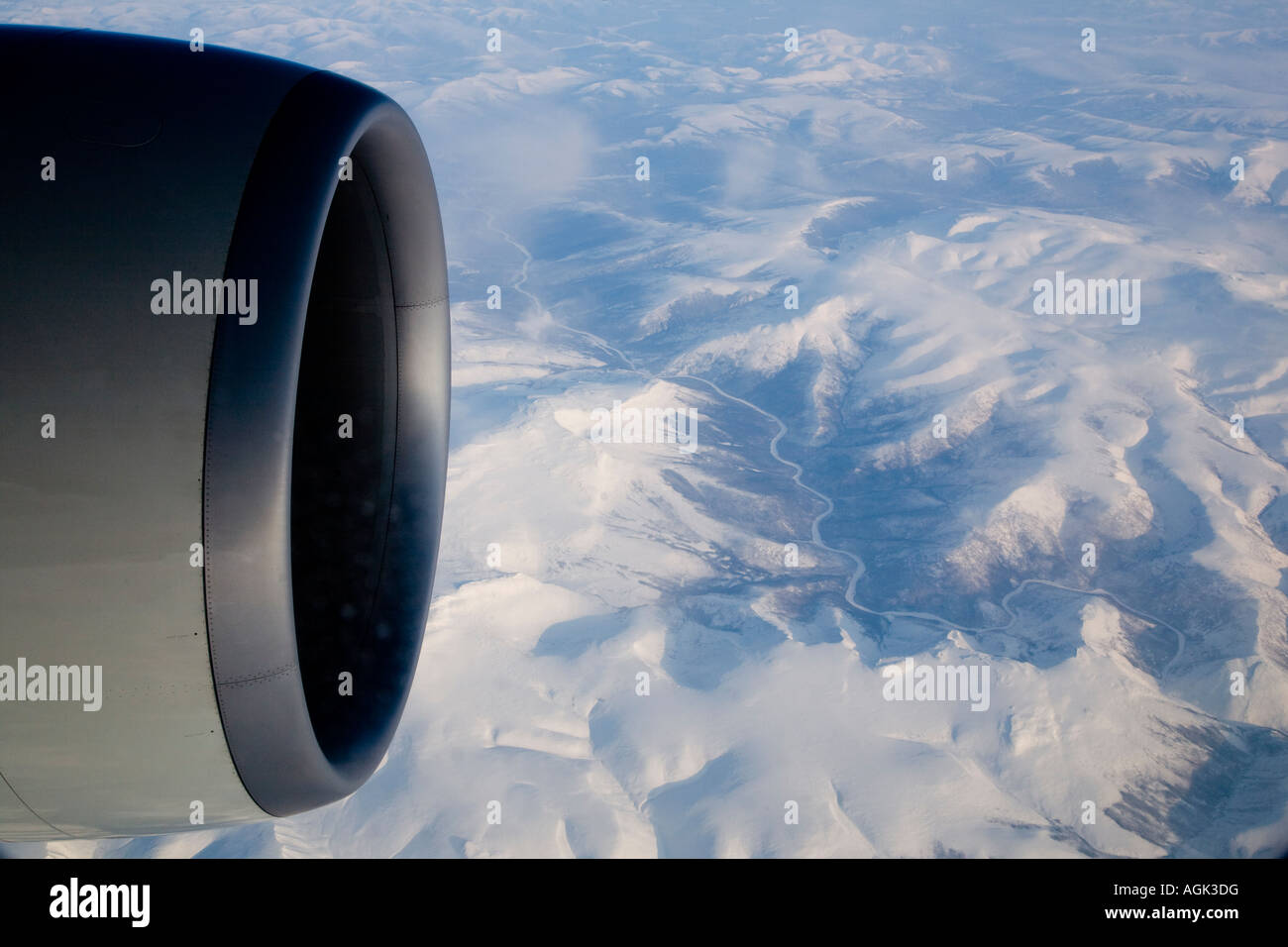 graphic shot of airplane wing and engine against muntain range covered in snow over siberia Stock Photo