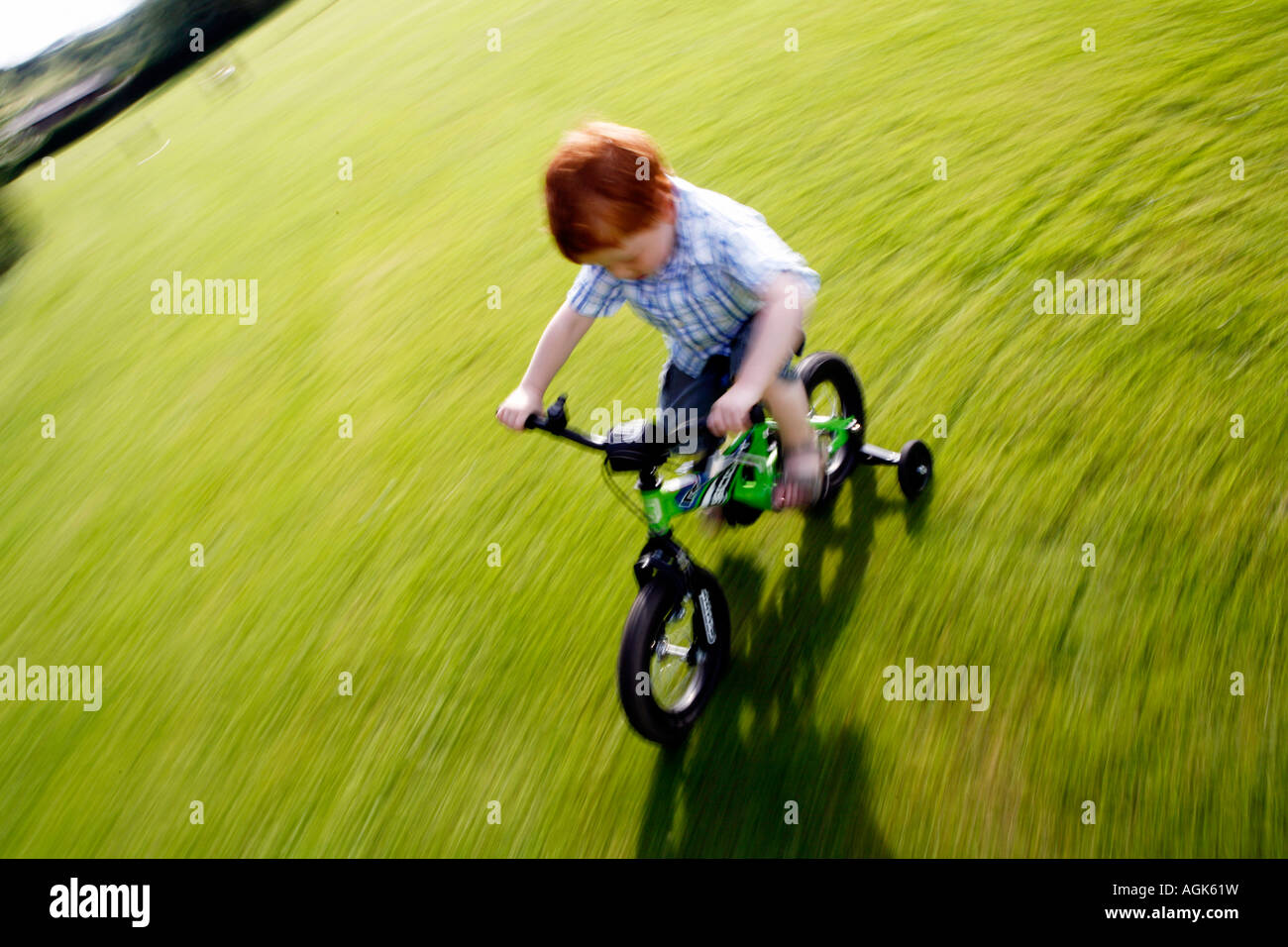 Boy cycling on a bike with stabilisers Stock Photo