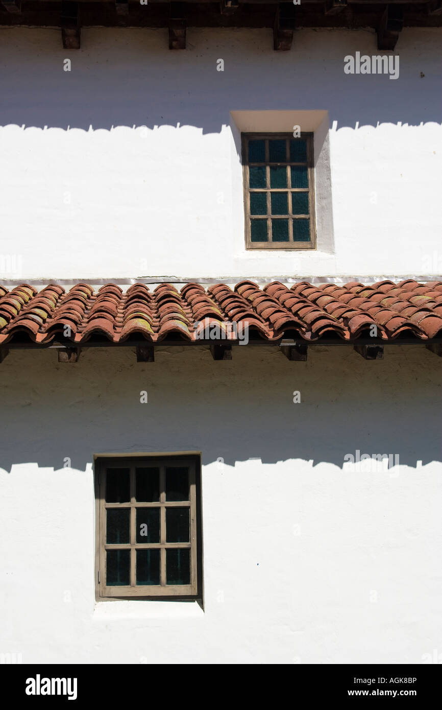 Two wood windows and Spanish tile roofs casting shadows on white walls