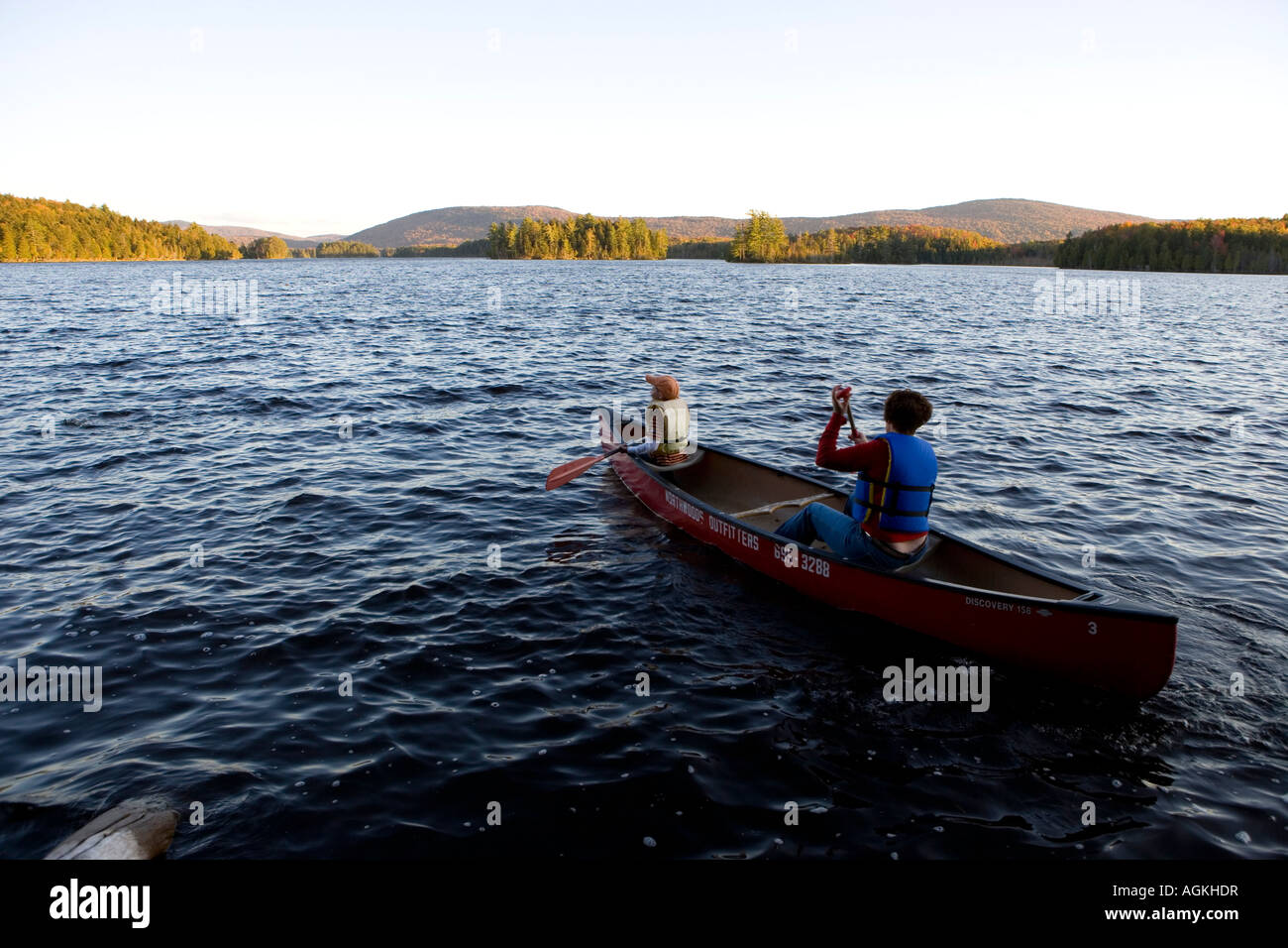 A woman and her son paddle a canoe on Prong Pond in Maine USA Stock