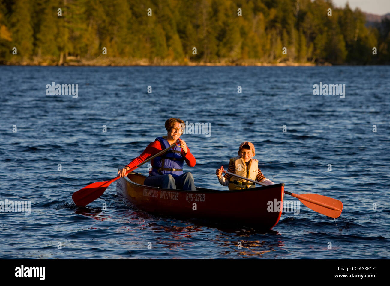 A woman and her son paddle a canoe on Prong Pond in Maine USA Stock