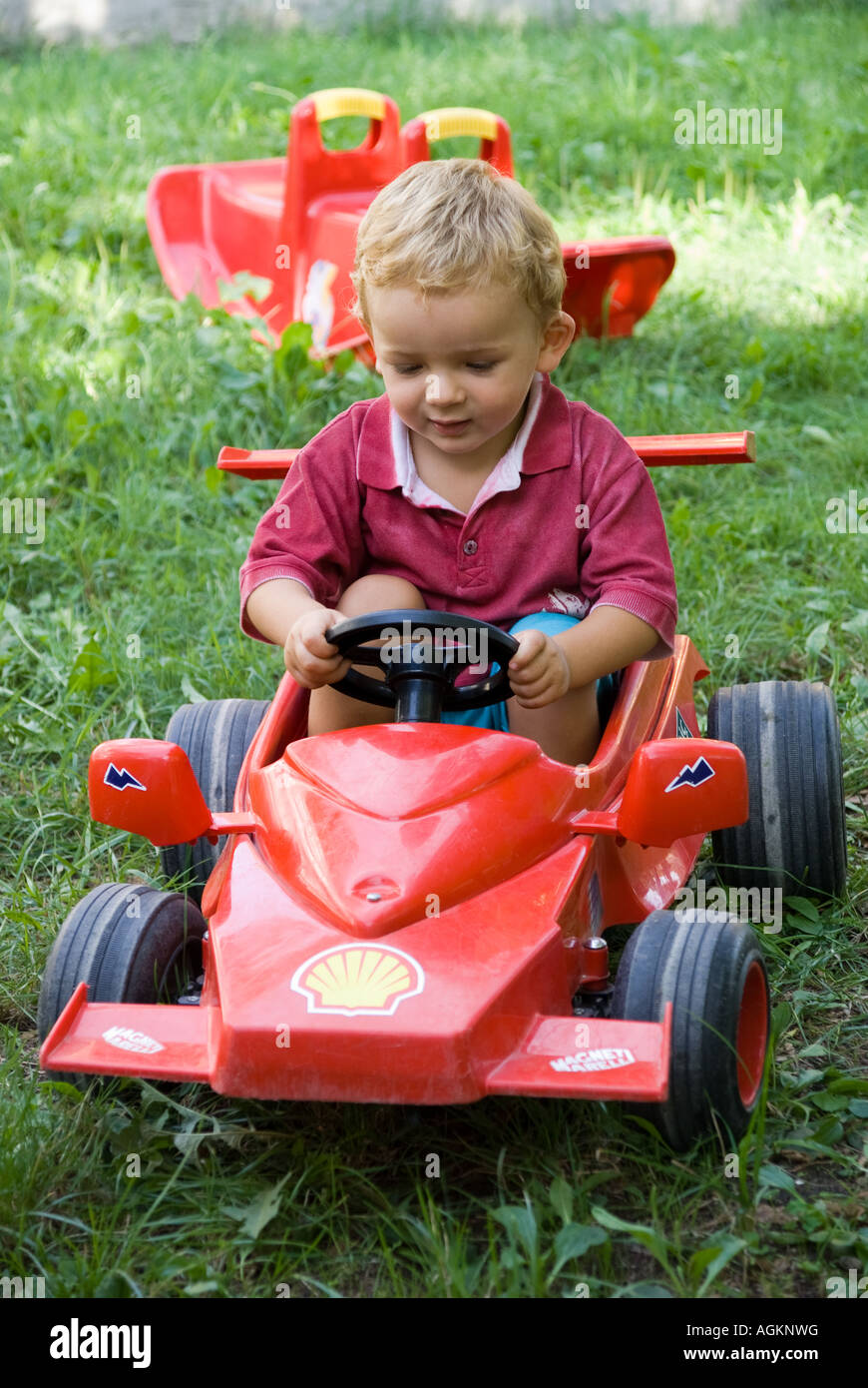 Little baby driving a red Ferrari car. Stock Photo