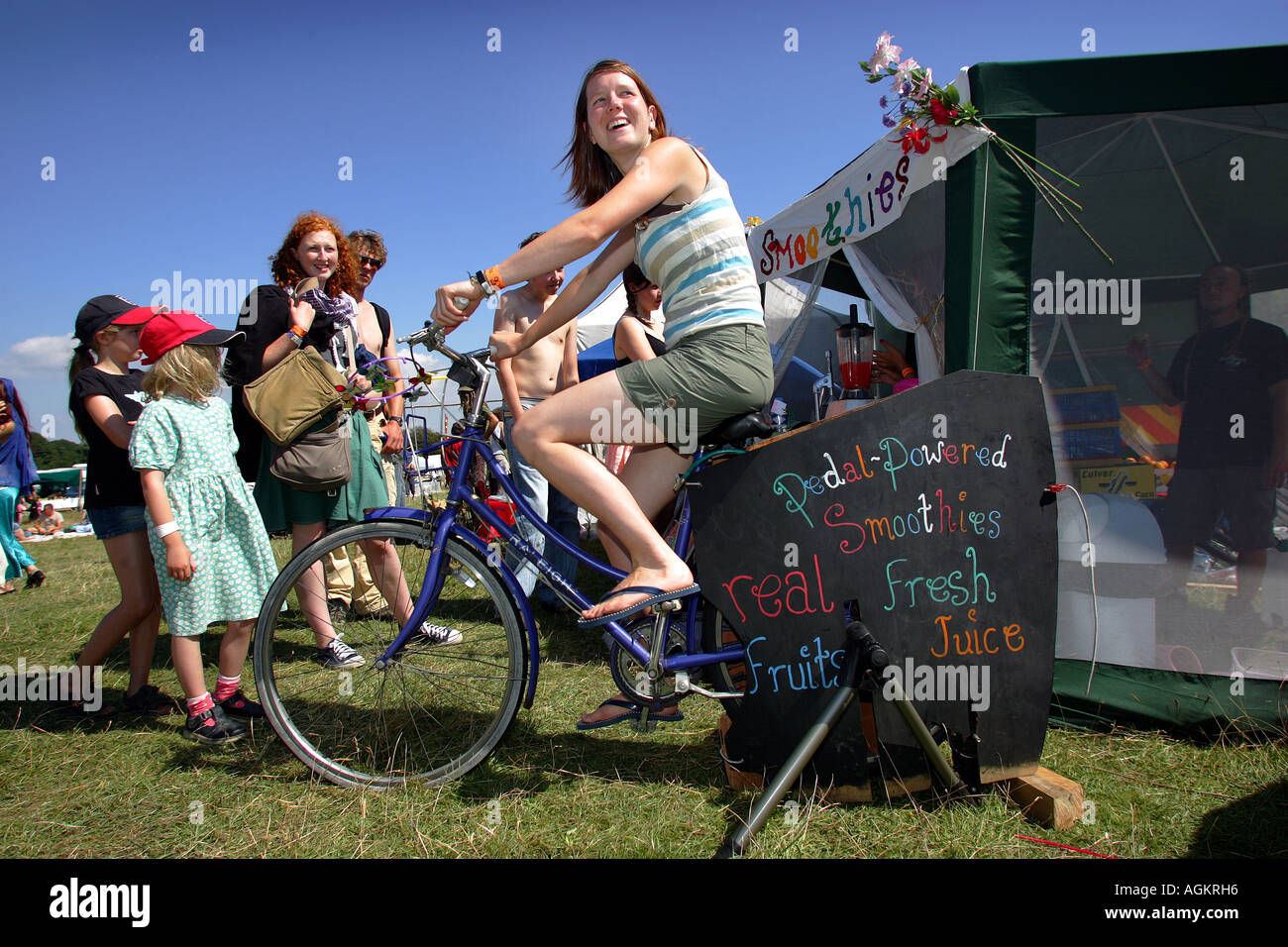 A customer blends her fruit smoothie using a static bike at The Big Green Gathering festival near Cheddar in Somerset UK Stock Photo