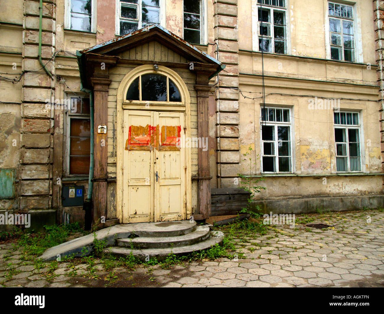 Entrance to an abandoned masonry hospital building in Suwalki, Poland, with stone courtyard and arched doorway. Stock Photo