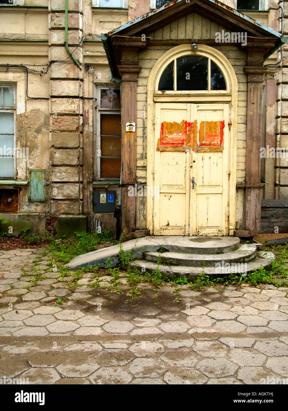 Entrance to an abandoned masonry hospital building in Suwalki, Poland, with stone courtyard and arched doorway. Stock Photo