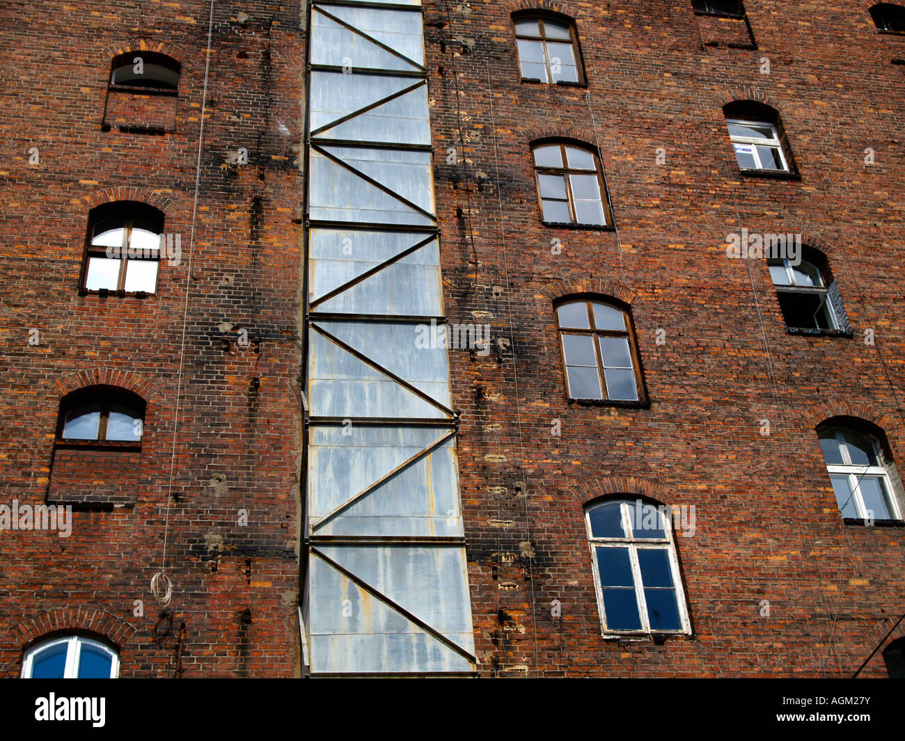 Windows and steel chimney on old brown-red brick high-rise building ...