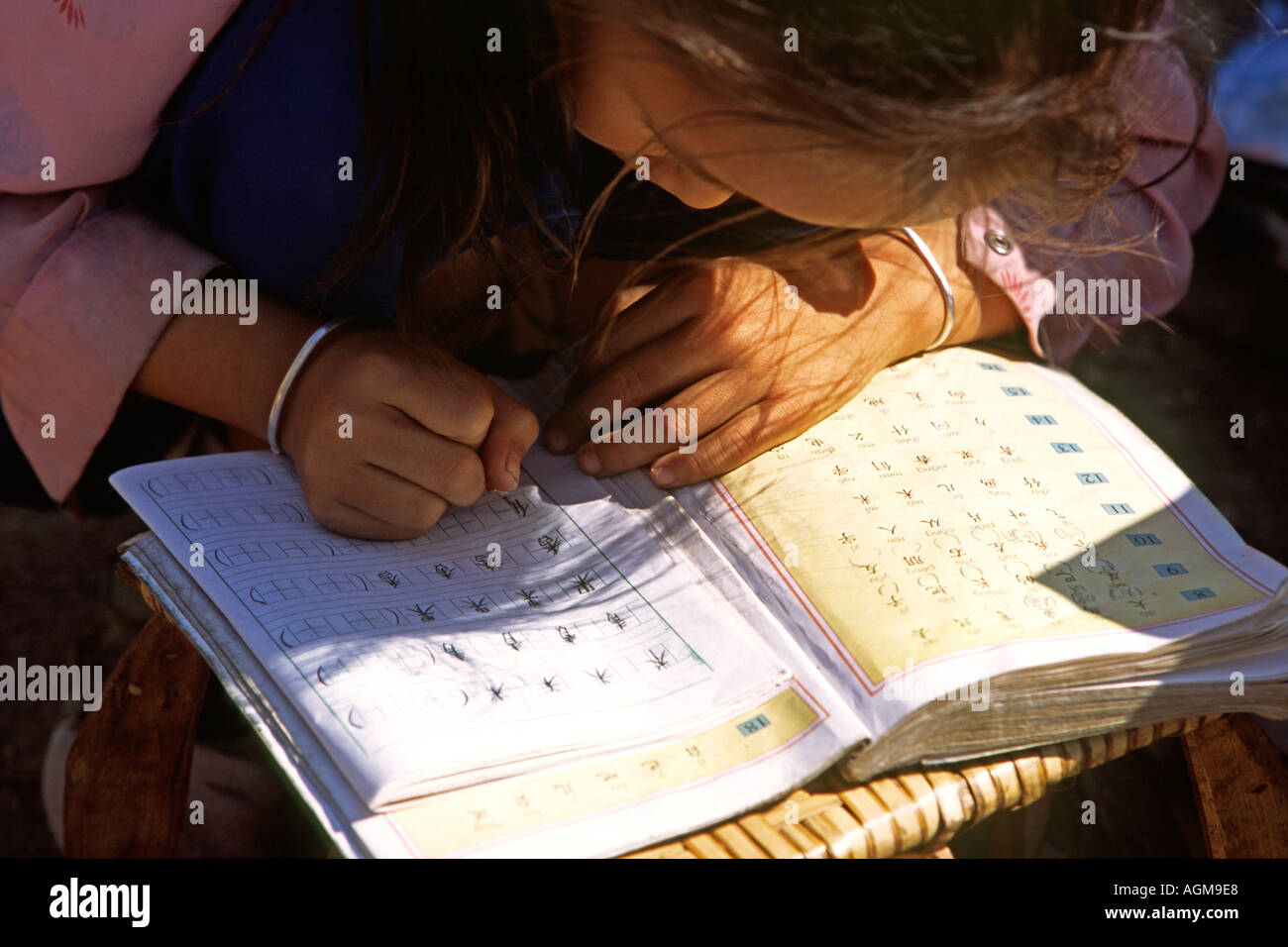 China Yunnan Xishuangbanna Gasa village young girl doing writing homework Stock Photo