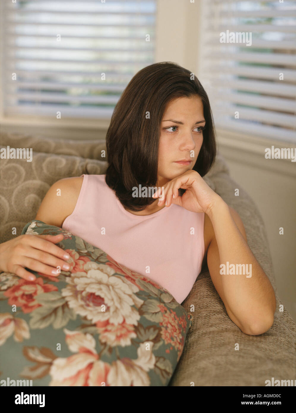 Moody young woman sitting on couch Stock Photo