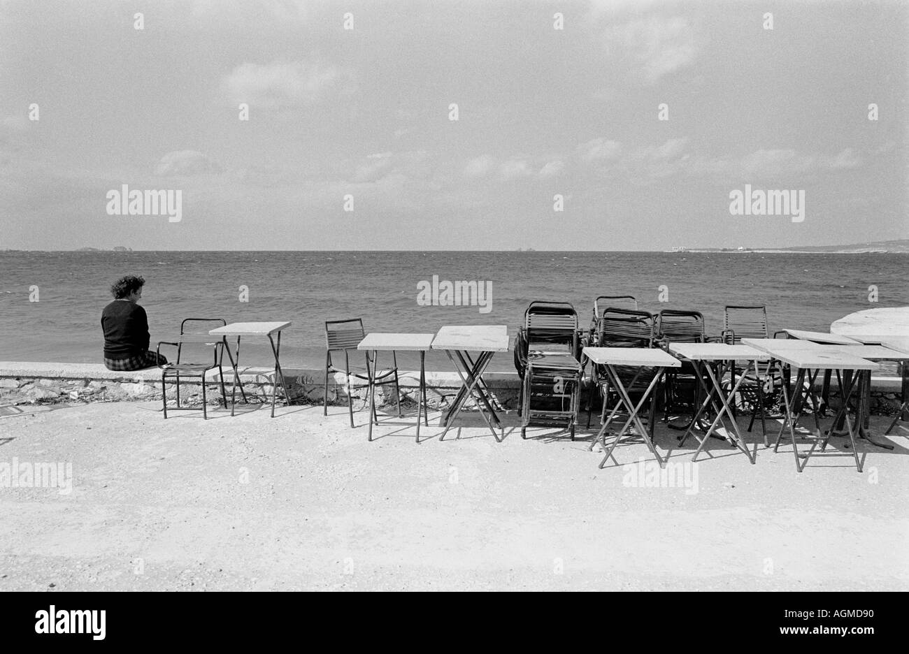 Greek woman sitting alone by a deserted taverna Paros Greece, 1983. Concept or conceptual image. Stock Photo