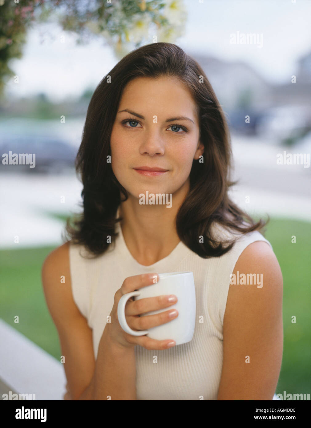 Young woman drinking hot beverage on front porch Stock Photo