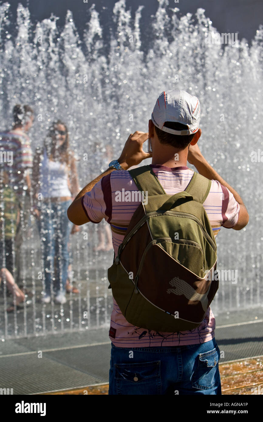 Tourist taking picture of girlfriend standing in fountain outside London's Royal Festival Hall Stock Photo